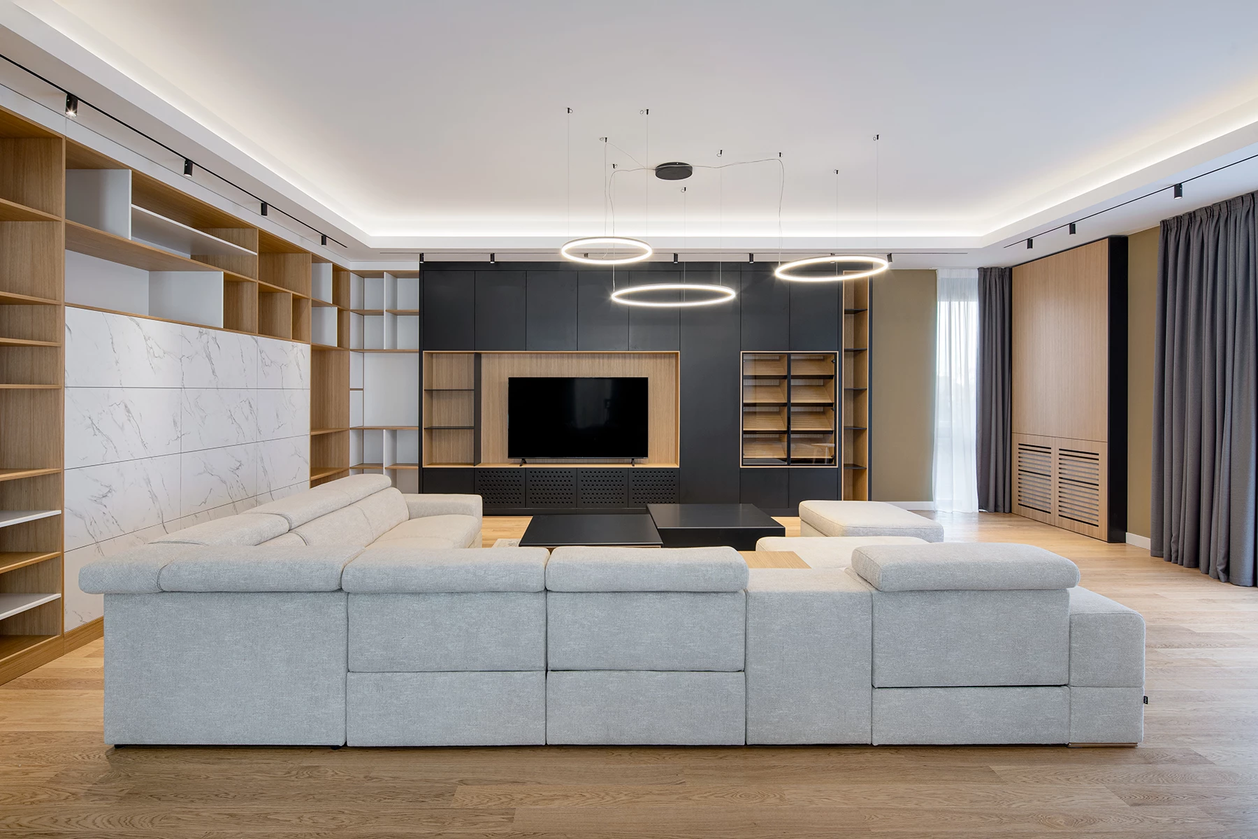 Living room in the SPV house with upholstered seating, wood shelving, and TV area