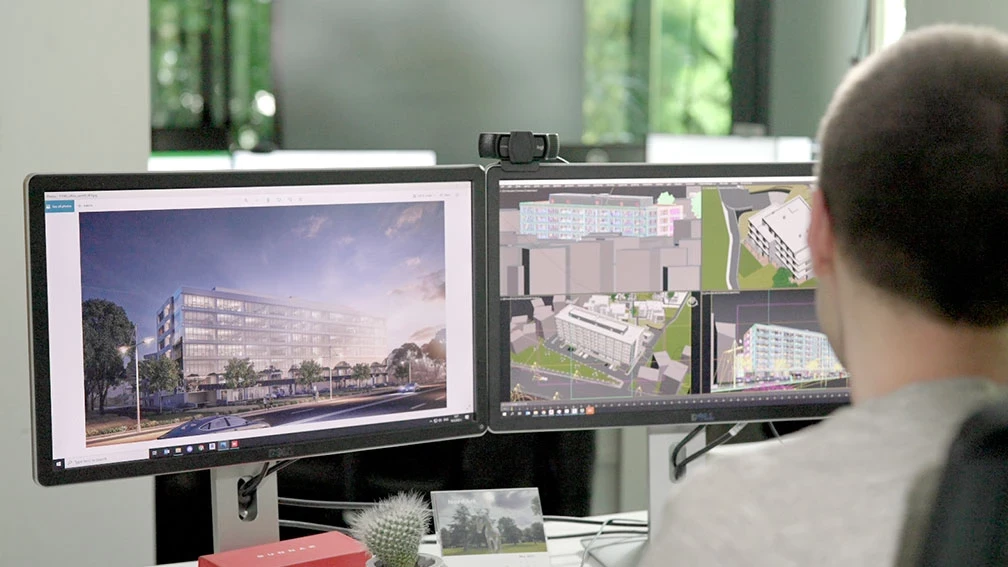 Specialist developing an architectural 3D visualization and building model on two monitors