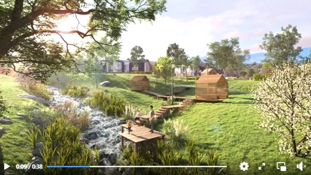Frame from a 3D animation of a park with a stream, wooden paths, and small buildings