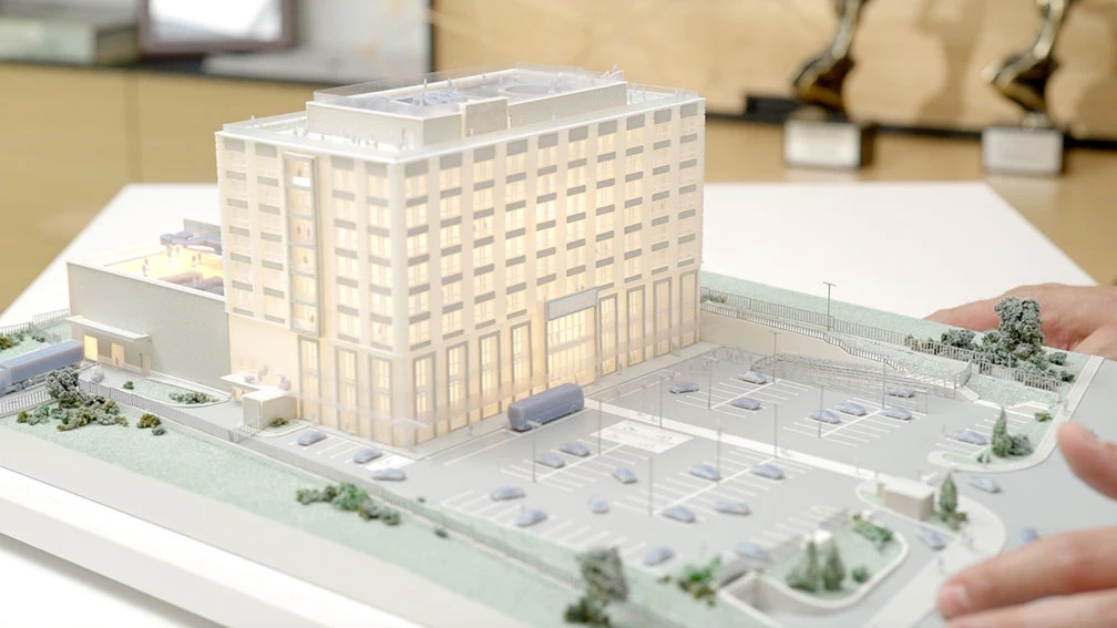 3D-printed architectural model of a multistory building with parking and landscaping
