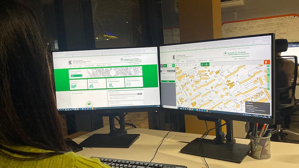 Specialist reviewing a digital cadastral map on two monitors