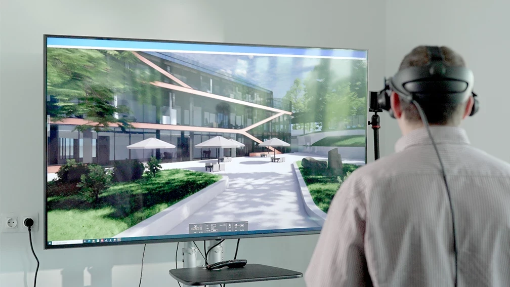 User wearing a VR headset and exploring a virtual architectural model on a screen