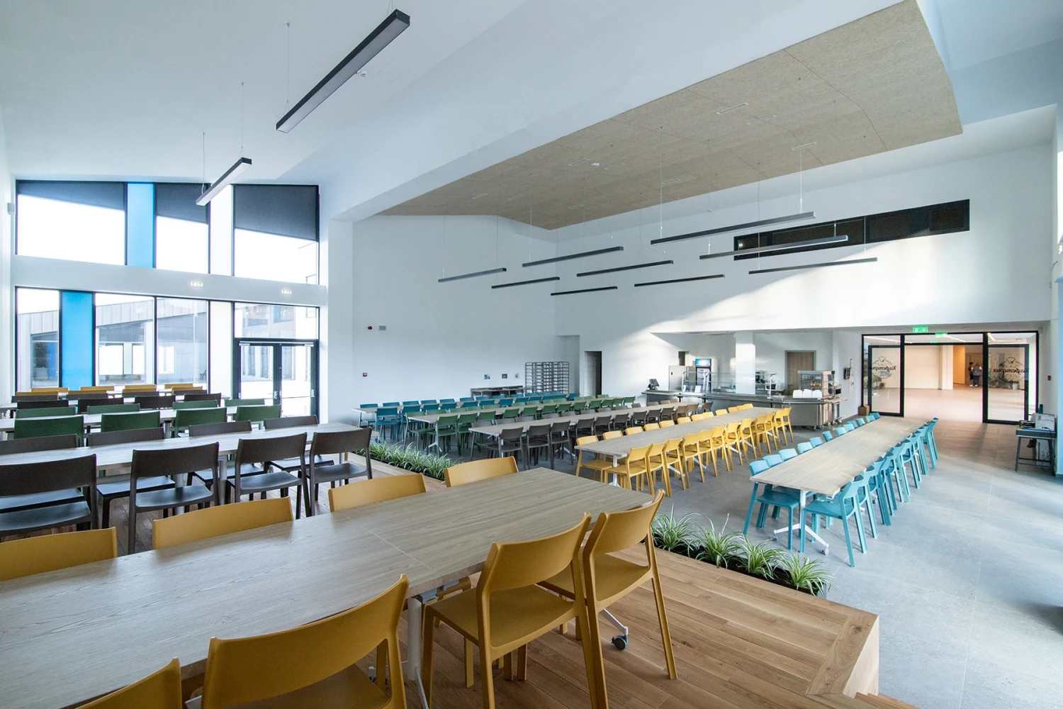 Зона за хранене в BRITANICA Park School с дълги маси и цветни места за сядане