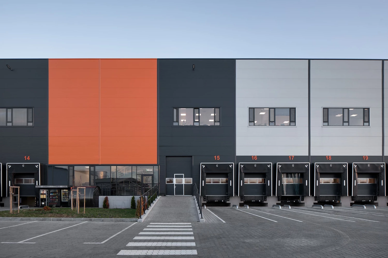 Facade detail of the Fresh&Frozen facility with orange volume and loading docks