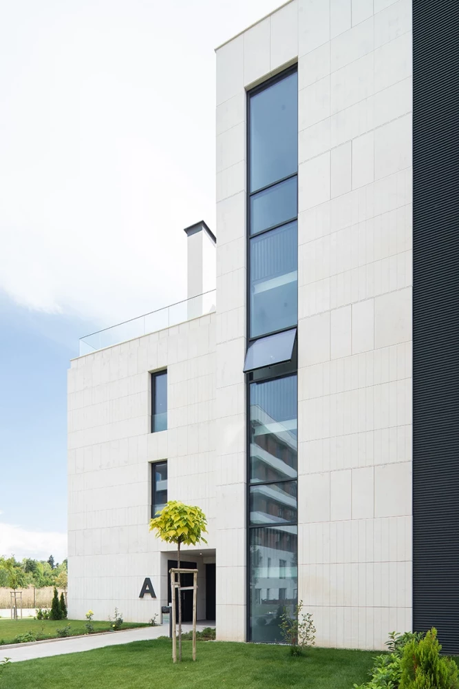 Фасаден детайл на GORA с бяла облицовка и вертикално остъкляване