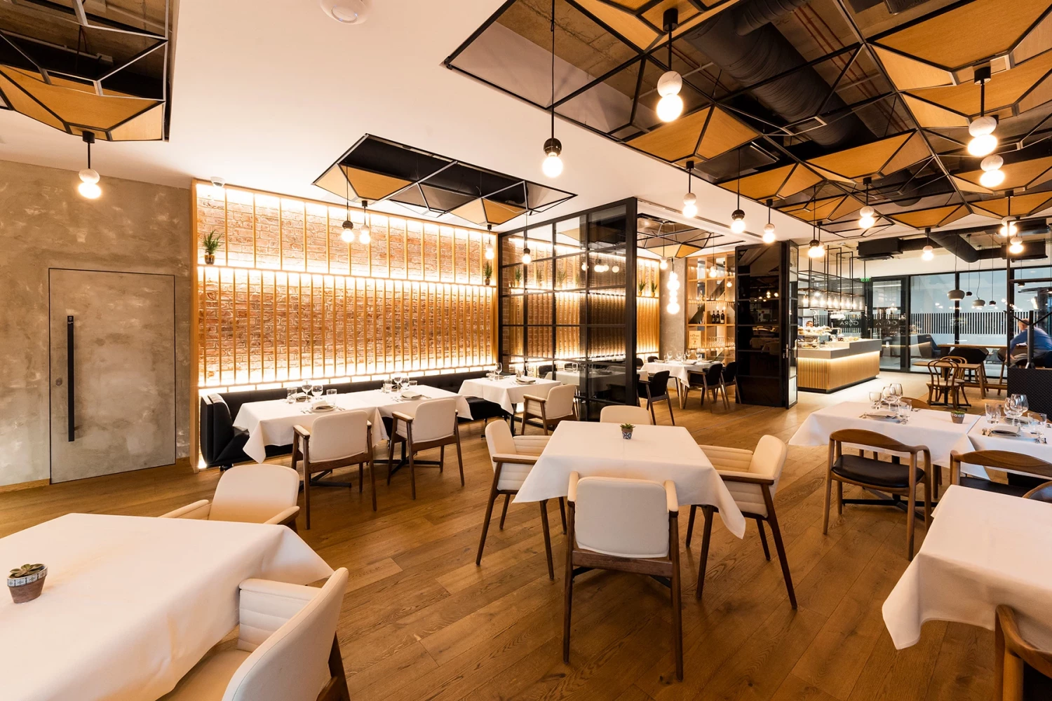 Dining area at GORA Restaurant with upholstered seating and decorative wood wall