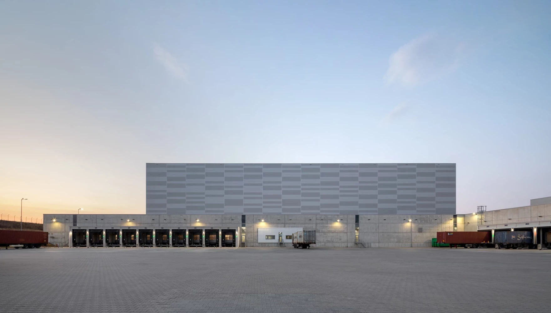 High-bay warehouse and loading area at the JYSK Logistics Base at dusk