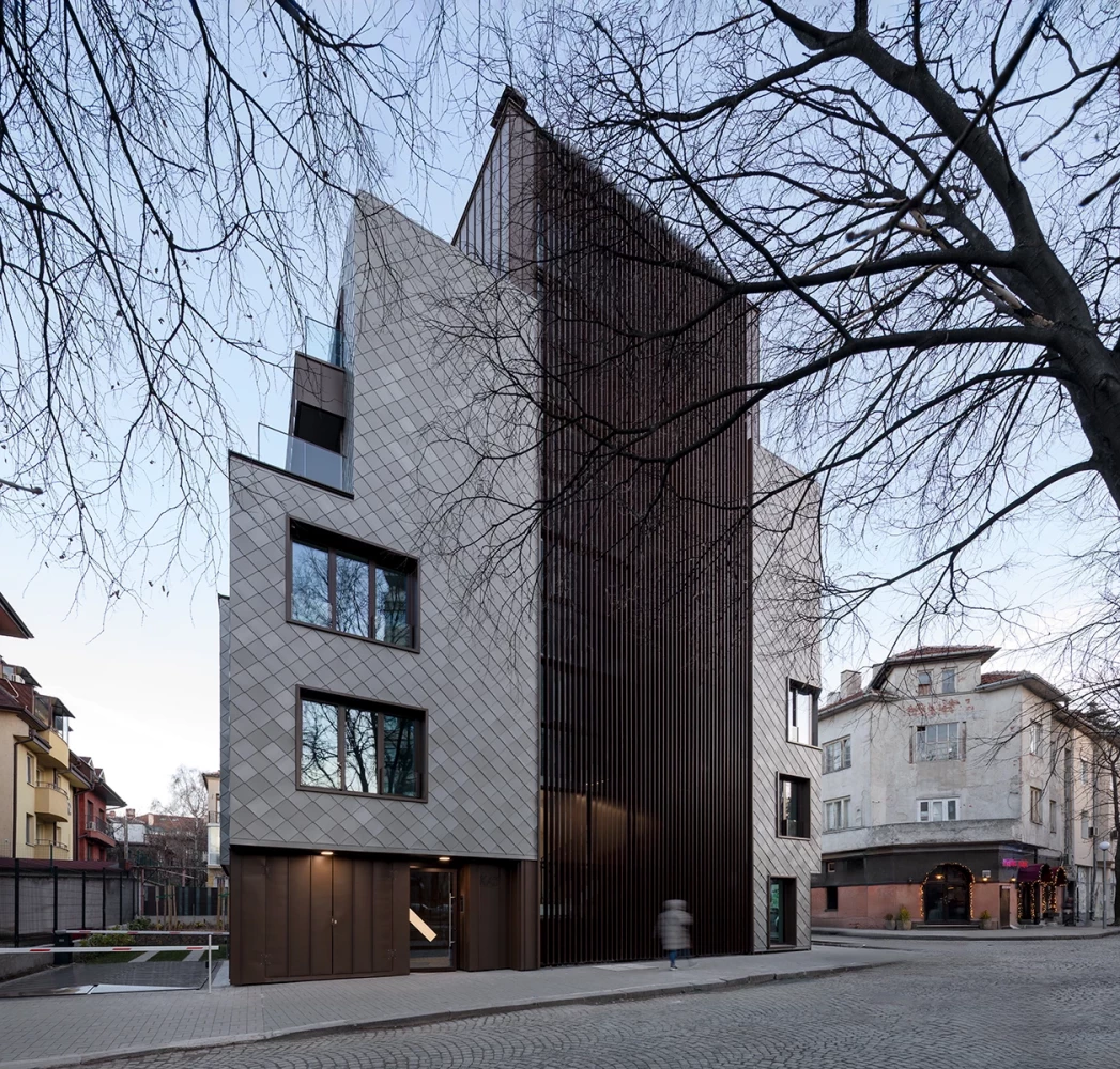 View of KA11 from the adjacent street with a titanium-zinc facade and dark vertical section