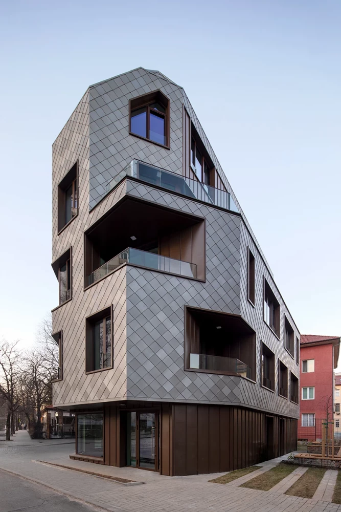 Corner view of KA11 with a titanium-zinc facade and recessed balconies