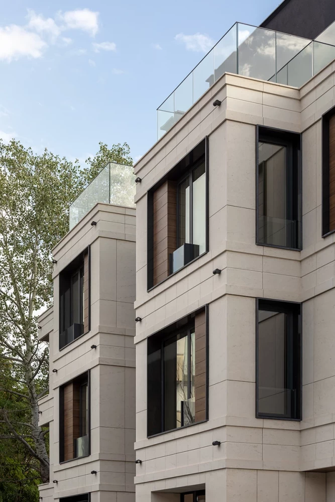 Facade detail with stone cladding and dark window frames at Sunset Garden by IPA - Architecture and more