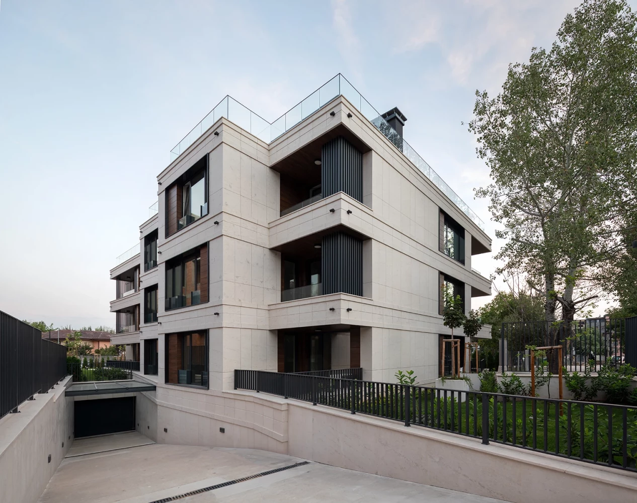 Corner view of Sunset Garden with glazed balconies and light stone cladding by IPA - Architecture and more