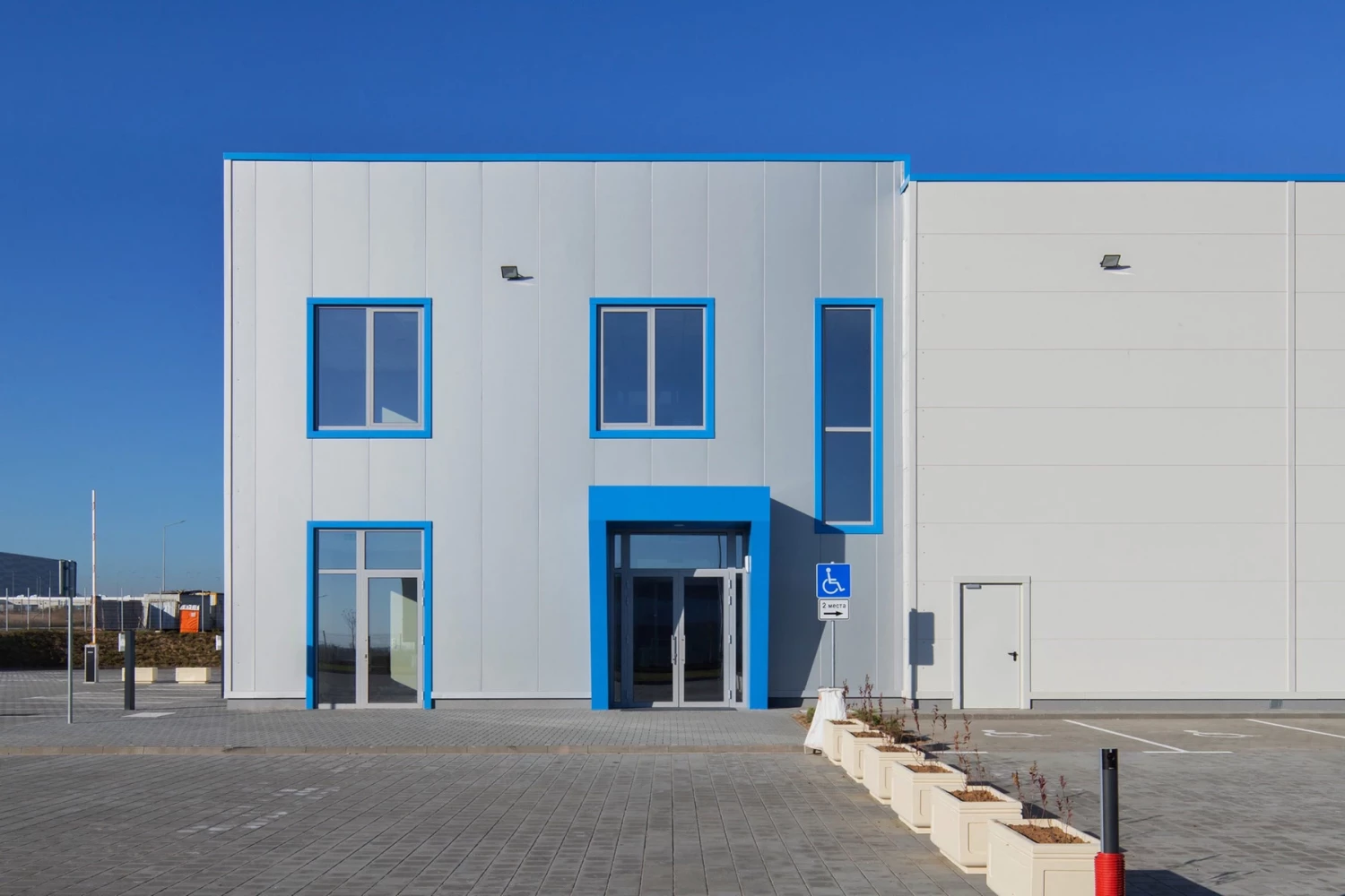 Вход към административната част на Thermo King с изнесена рамка и син фасаден акцент