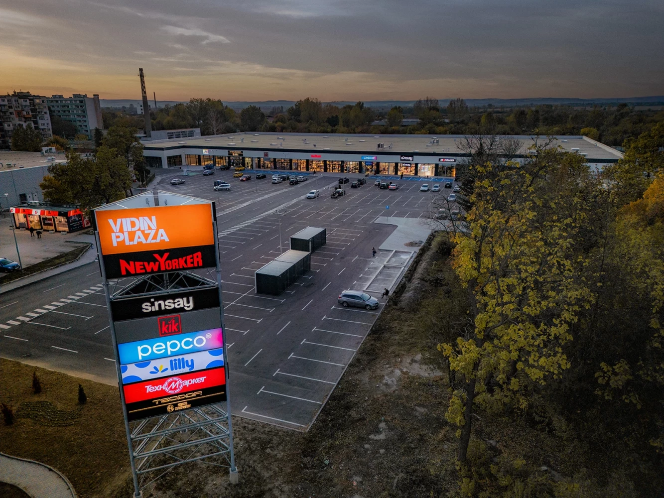 Entrance area of Vidin Plaza with retail signage, parking, and commercial buildings by IPA - Architecture and more