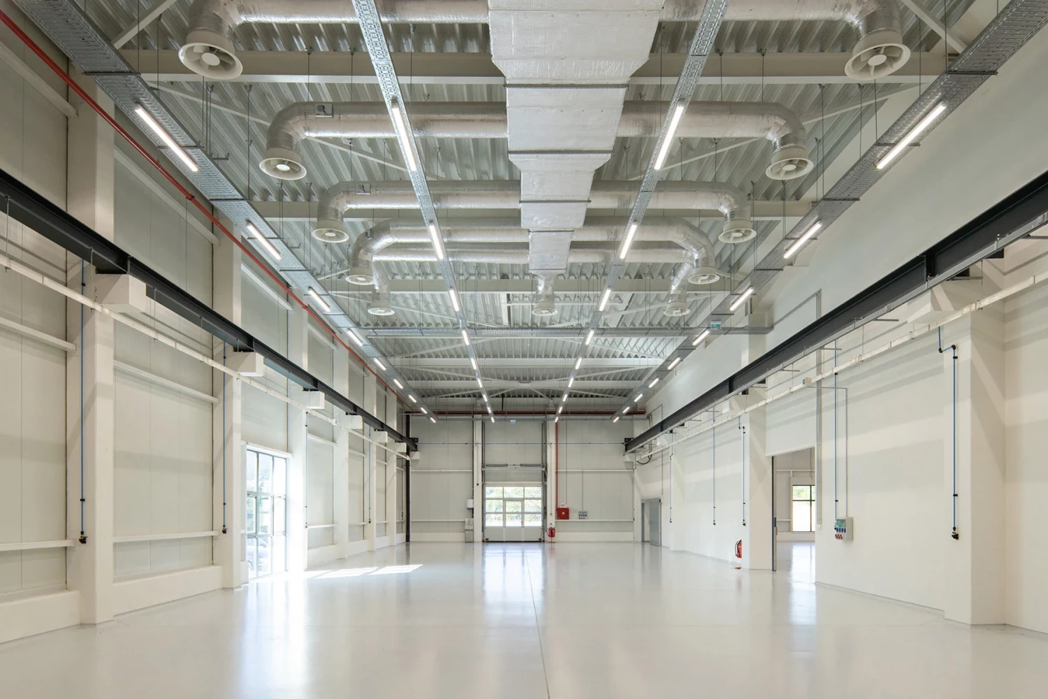 Spacious VolaPlast production hall with exposed building systems by IPA - Architecture and more