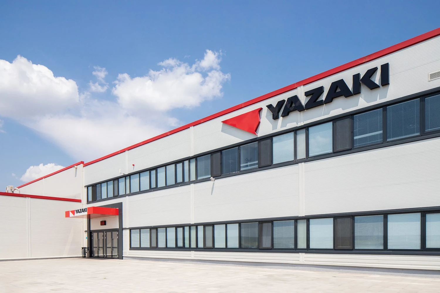 Детайл от фасадата на производствената база Yazaki с черна дограма и червен покривен кант