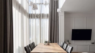 Dining area in Apartment R2 with a large table, panoramic windows, and built-in TV wall