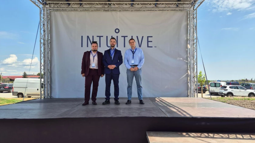 Трима участници на сцената пред логото на Intuitive по време на откриването на базата в Първомай