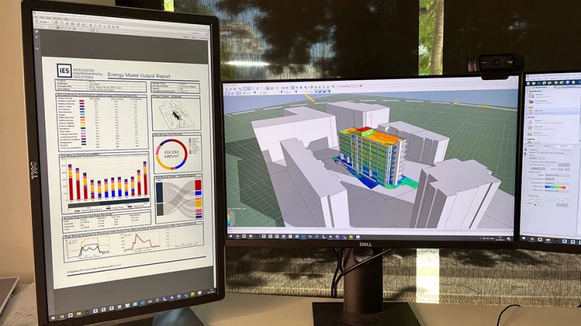 Building energy model and simulation results displayed on three monitors
