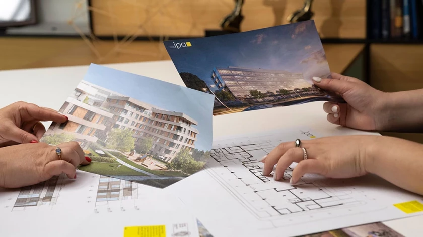 Two people reviewing printed architectural visualizations over project drawings
