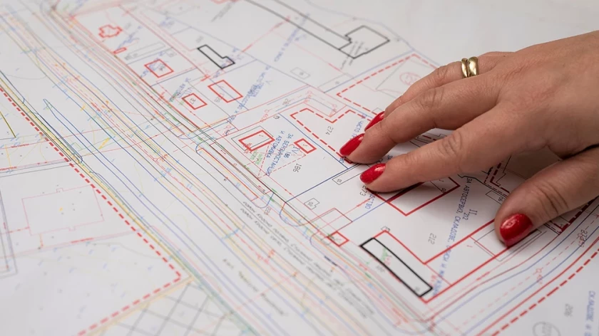 Hand pointing to planning and building lines on a detailed development plan