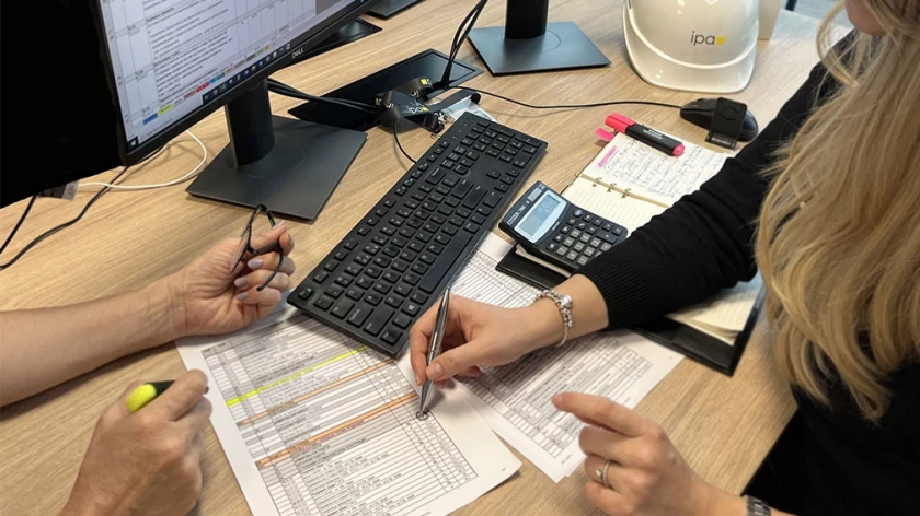 Two specialists reviewing project tables and calculations during a work meeting